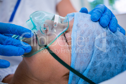 Patient wearing oxygen mask lying on hospital bed