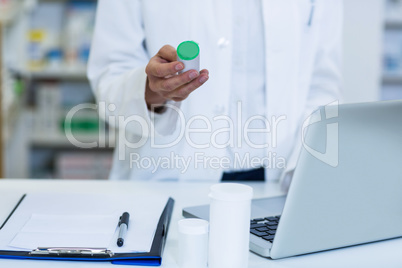 Smiling pharmacist standing at counter in pharmacy