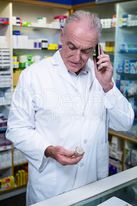 Pharmacist talking on mobile phone while checking medicine