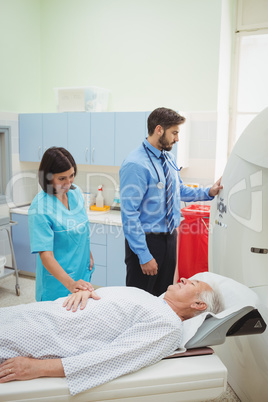 A patient is loaded into an mri machine while doctor and technic