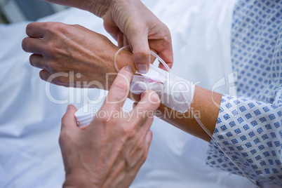 Nurse attaching iv drip on patient s hand