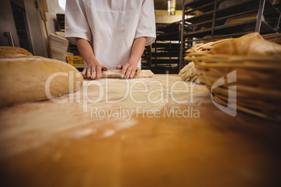 Mid-section of female baker kneading a dough