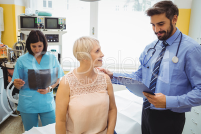 Male doctor interacting with a patient while nurse looking at x-