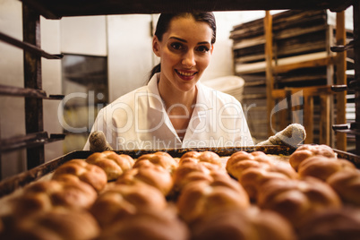 Portrait of female baker holding a tray of michetta