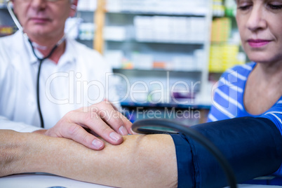 Pharmacist checking blood pressure of customer