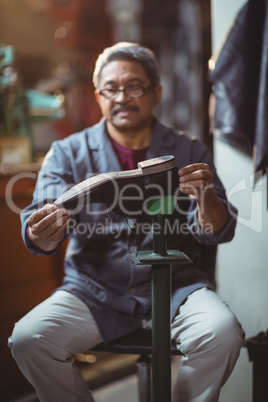 Shoemaker examining a shoe