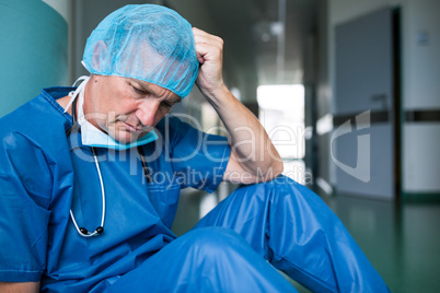 Sad surgeon sitting on floor in corridor