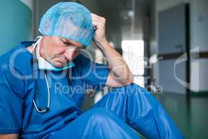 Sad surgeon sitting on floor in corridor