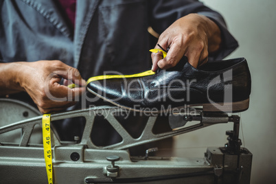 Shoemaker measuring a shoe with measure tape