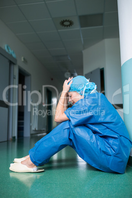 Sad surgeon sitting on floor in corridor