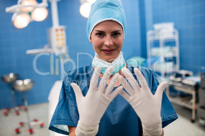 Portrait of female surgeon showing surgical gloves in operation
