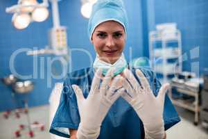 Portrait of female surgeon showing surgical gloves in operation