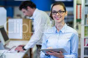 Smiling pharmacist holding digital tablet in pharmacy