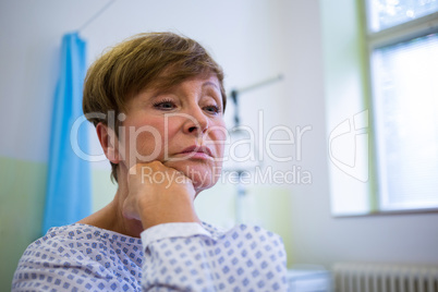 Close-up of sad senior patient sitting on a bed