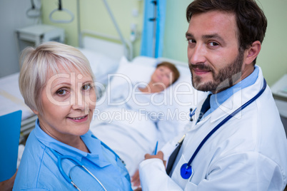 Portrait of doctor and nurse standing in hospital room