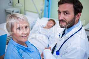 Portrait of doctor and nurse standing in hospital room