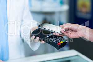 Woman paying bill through smartphone using NFC technology