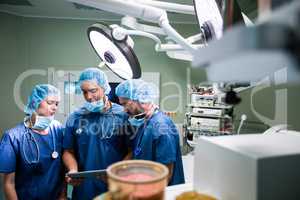 Surgeons discussing over digital tablet in operation room