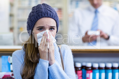 Customer covering her nose while sneezing in pharmacy