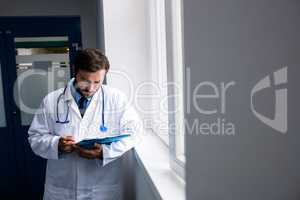 Doctor standing in corridor looking at clipboard