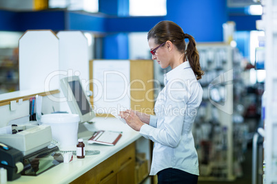 Pharmacist standing at counter and looking prescription