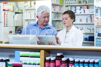 Pharmacists using digital tablet at counter