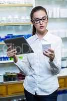 Pharmacist using digital tablet while checking medicine