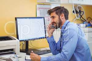 Doctor sitting at his desk and talking on phone