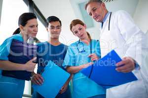 Doctor and surgeons discussing with report in corridor