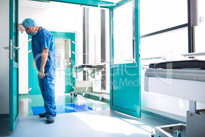 Sad surgeon leaning against the glass door