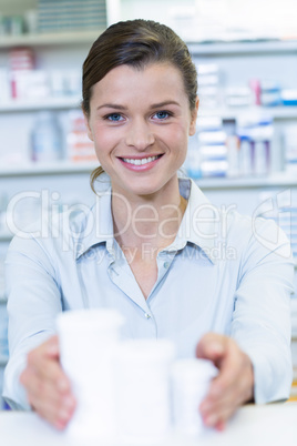 Smiling pharmacist holding medicine container in pharmacy