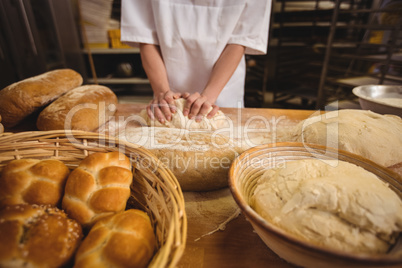 Mid-section of female baker kneading a dough