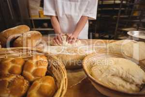 Mid-section of female baker kneading a dough