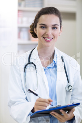 Pharmacist writing on clipboard in pharmacy