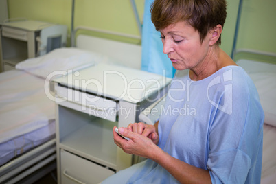 Sad senior patient using mobile phone