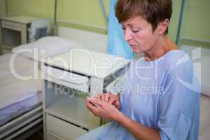 Sad senior patient using mobile phone