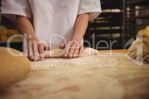 Mid-section of female baker kneading a dough
