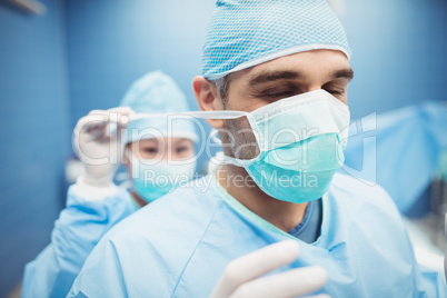 Nurse helping a surgeon in tying surgical mask