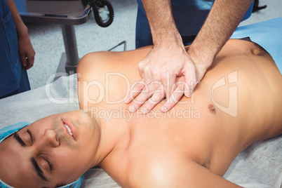 Male surgeon performing cardiopulmonary resuscitation on an unco
