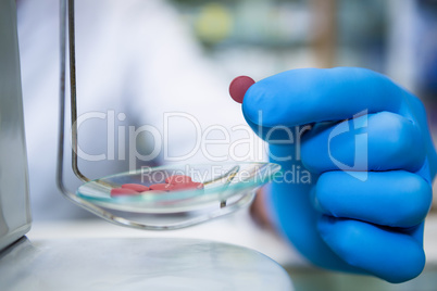 Pharmacist measuring tablets with pharmacy scale