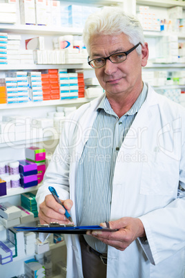 Pharmacist writing on clipboard in pharmacy