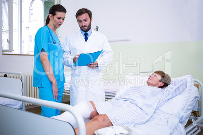 Doctor and nurse discussing over patient s leg