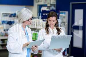 Pharmacists using digital tablet and laptop
