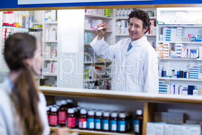 Pharmacist standing at counter and showing medicine box