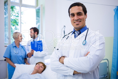 Smiling doctor standing with arms crossed in hospital