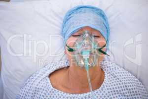 Patient wearing oxygen mask lying on hospital bed