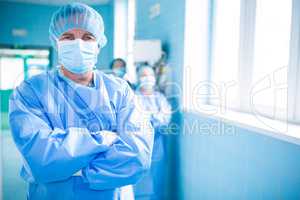 Portrait of surgeon standing with arms crossed in corridor