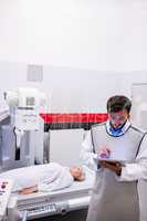 Doctor using digital tablet and patient lying on x ray machine