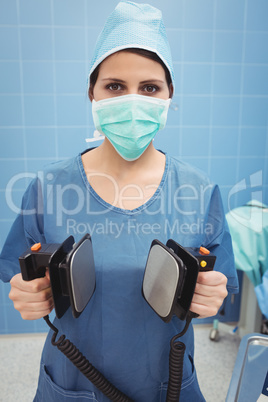 Portrait of female surgeon holding defibrillator