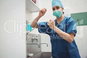 Portrait of female surgeon washing hands prior to operation usin